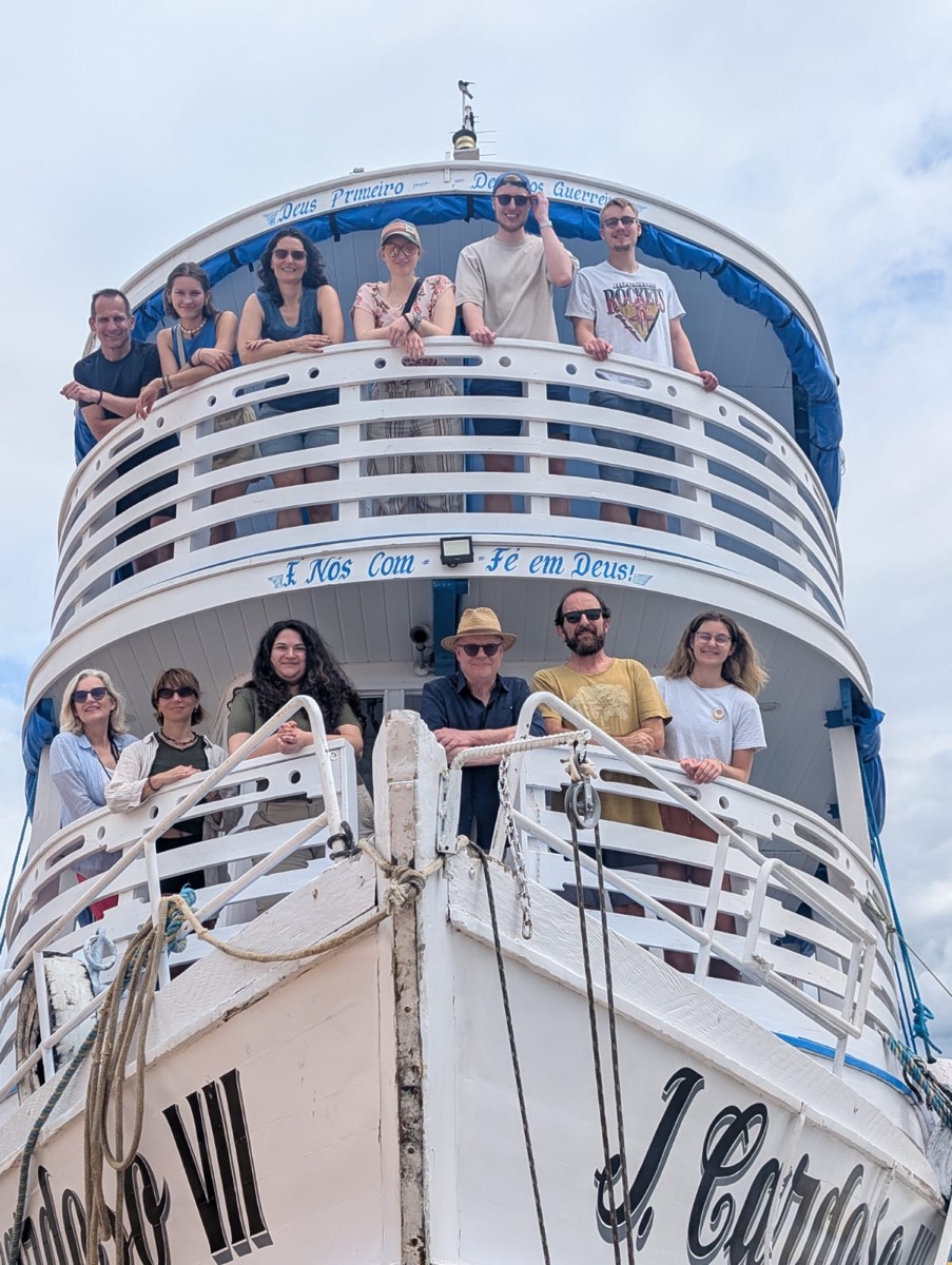 Eine Gruppe steht auf den Decks eines Ausflugsschiffs und blickt in die Kamera