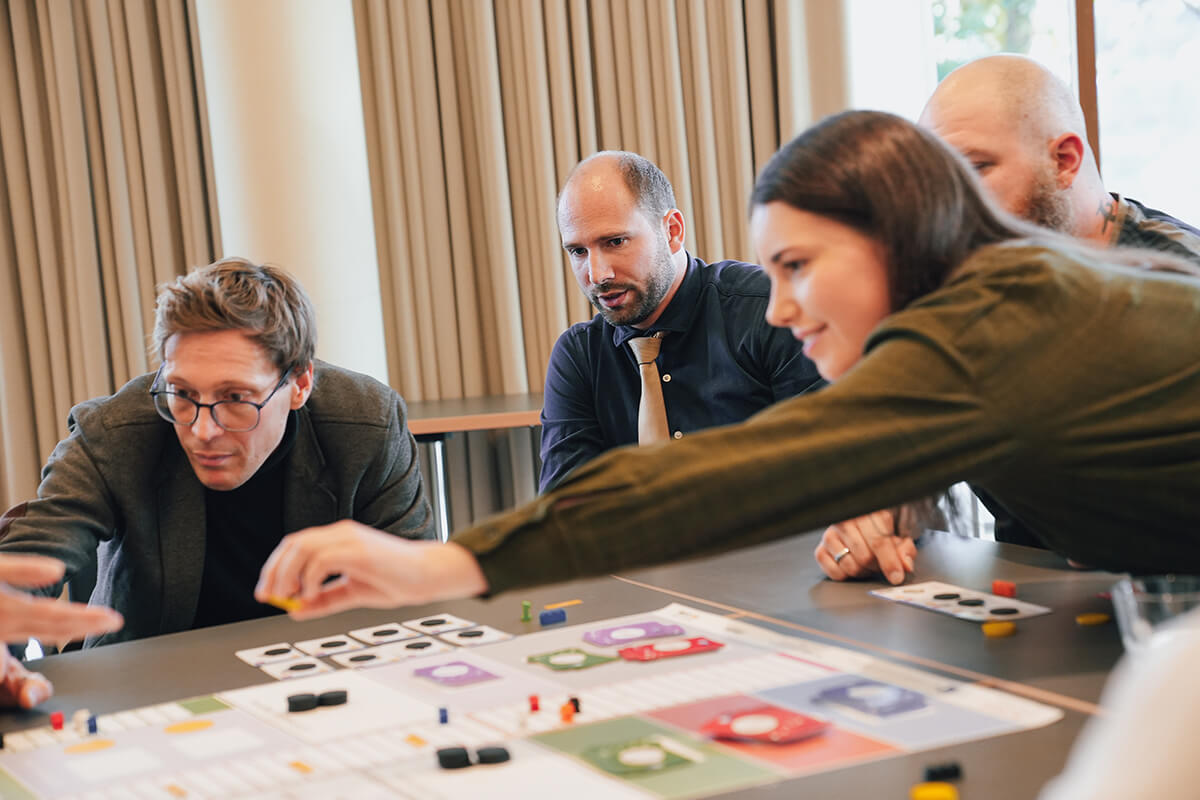 Team im Celsius-Workshop am Spielfeld Mehrere Teilnehmende sitzen an einem Tisch und greifen nach Spielsteinen auf dem Spielfeld von CELSIUS