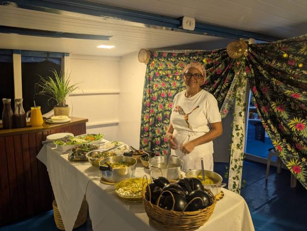 Frau steht an einem Buffet mit regionalen Speisen auf einem Boot im Amazonasgebiet