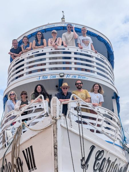 Eine Gruppe steht auf den Decks eines Ausflugsschiffs und blickt in die Kamera