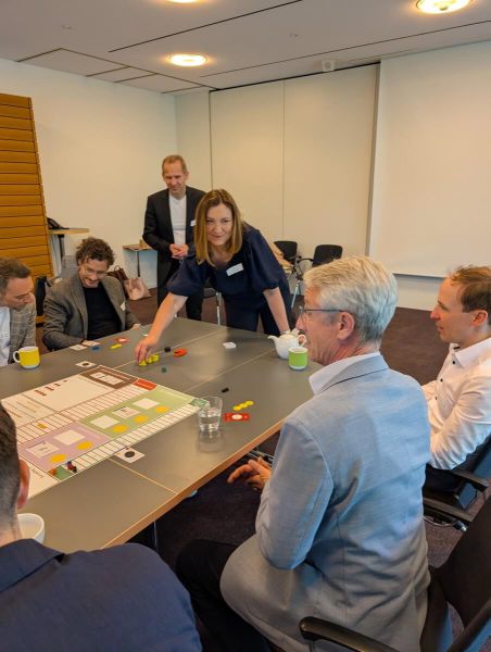 Teilnehmende spielen CELSIUS - Die 2 Grad Challenge an einem Tisch mit großem Spielbrett