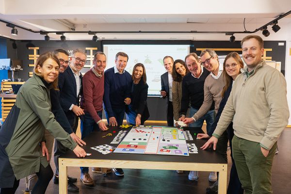 Eine Gruppe von Teilnehmenden steht um einen Tisch mit dem Spielfeld von Celsius - Die 2 Grad Challenge
