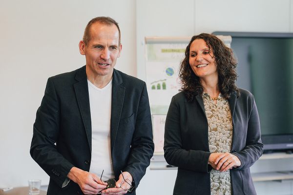 Zwei Workshop-Leitende stehen in einem Seminarraum und sprechen mit einer Gruppe