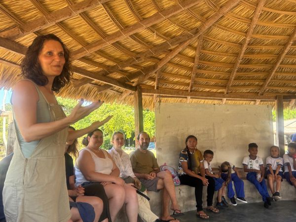Eine Frau spricht in einem offenen Gebäude mit Kindern und weiteren Erwachsenen im Amazonasgebiet